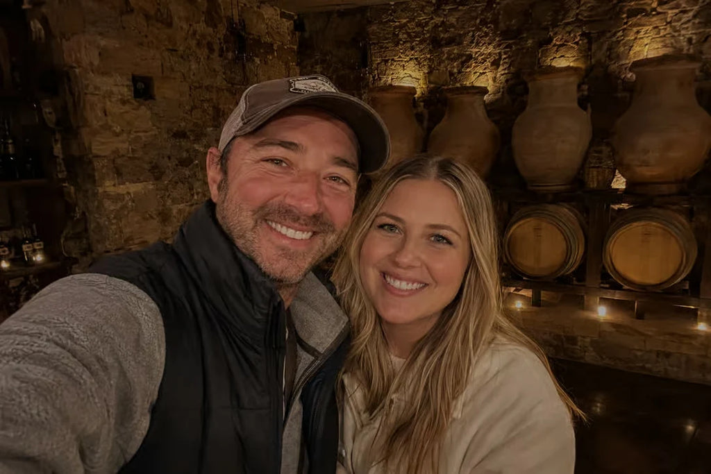 Two visitors smiling inside a traditional stone wine cellar during a Logroño winery experience
