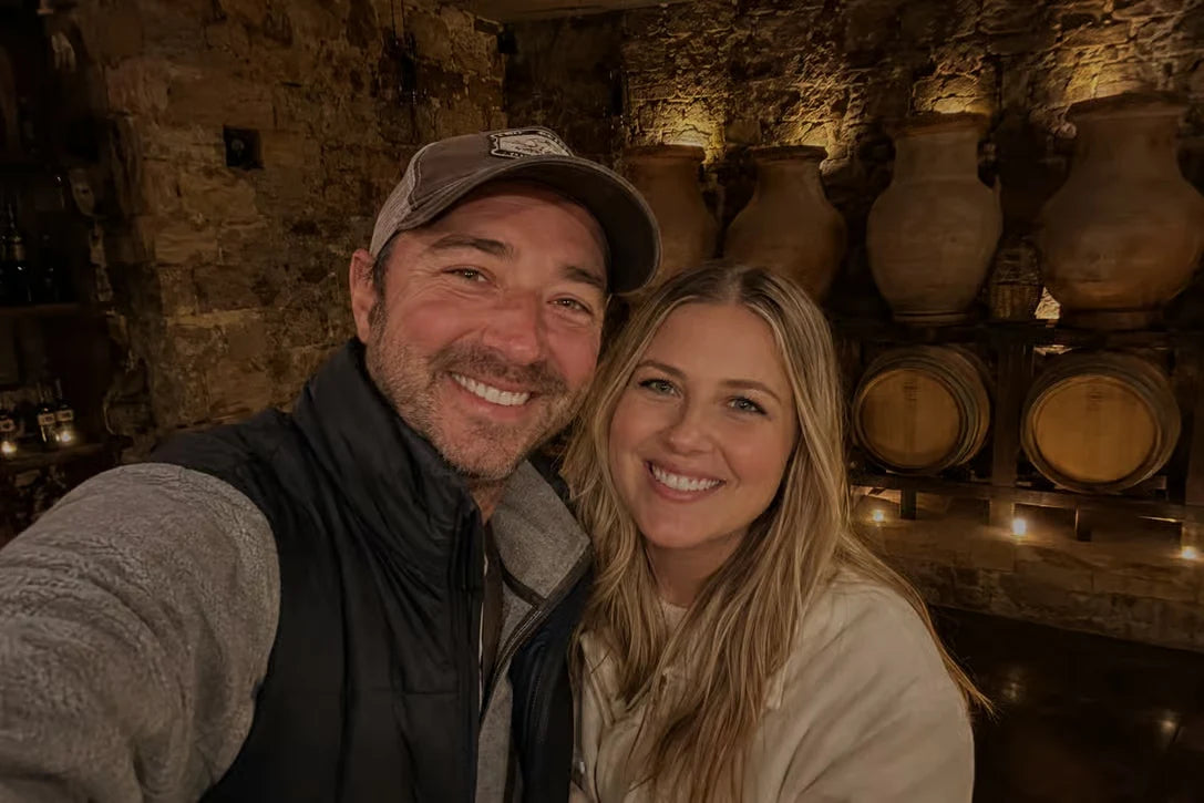 Two visitors smiling inside a traditional stone wine cellar during a Logroño winery experience