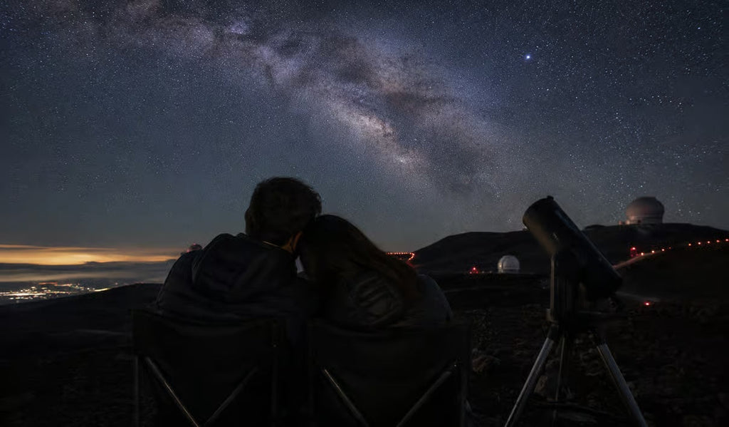 Two visitors stargazing beneath the Milky Way by Mauna Kea observatories