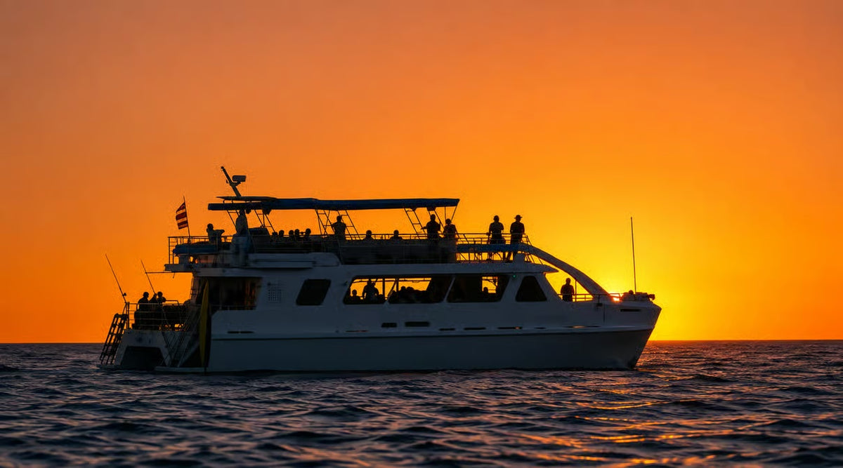 Kona sunset dinner cruise vessel silhouetted against an orange Pacific sunset