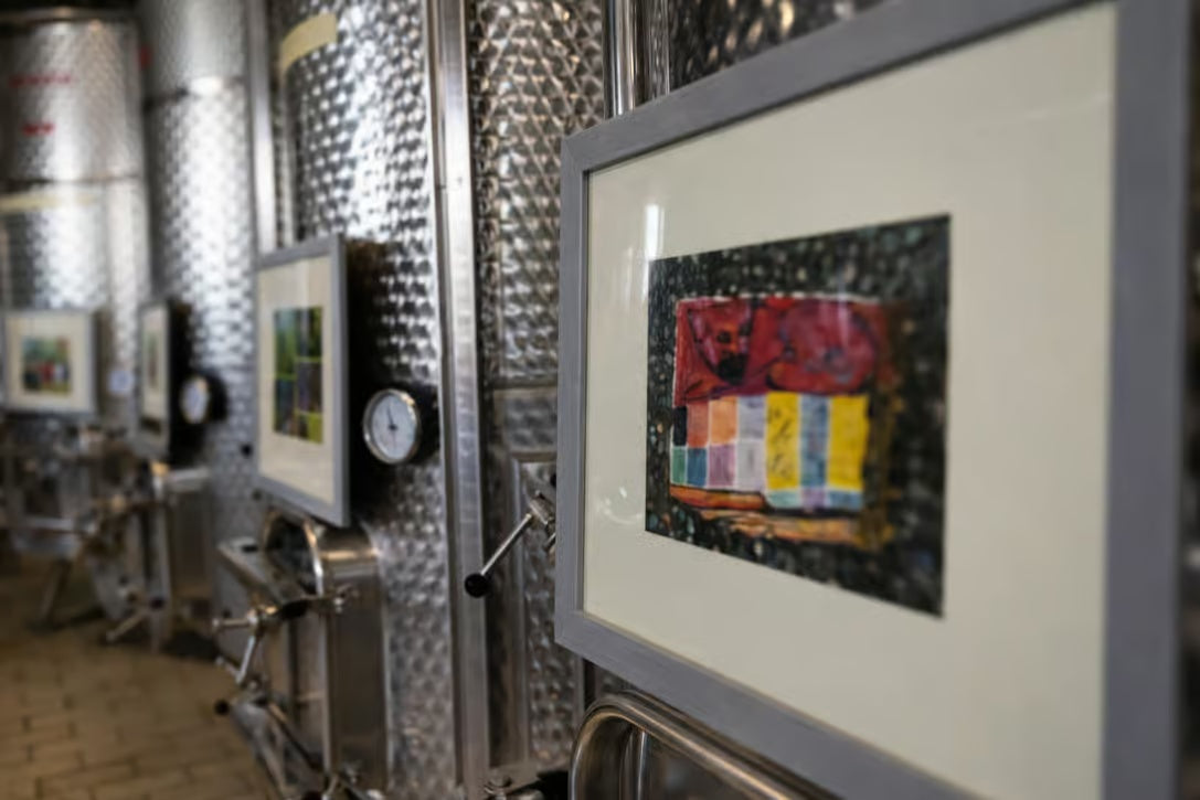 Art displayed inside a Tuscan winery cellar with stainless steel wine tanks