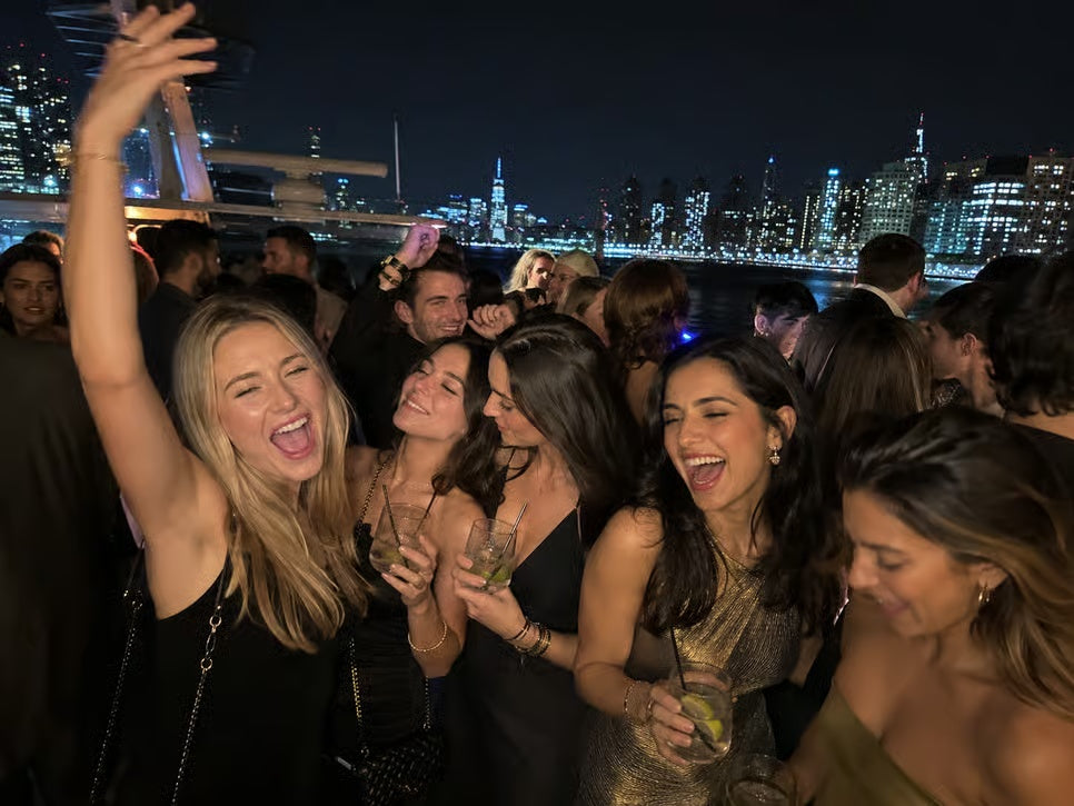 Guests celebrating on deck of New York City New Year's Eve party cruise with skyline at night